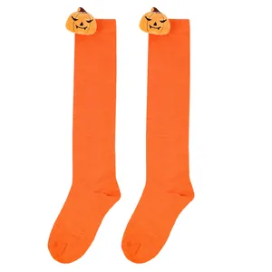 Detailed view of orange Halloween knee-high socks featuring a cute plush pumpkin doll