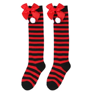 Detail view of red and black striped children's knee-high Christmas socks with bows