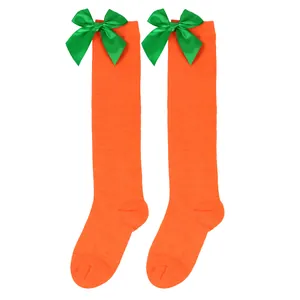 Bright orange carrot-themed girl's knee-high socks adorned with green satin bows
