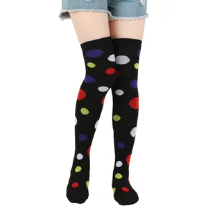 Close-up of colorful polka dot over-the-knee socks on model legs against white background