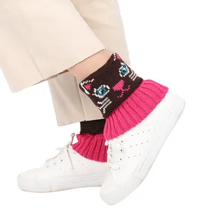 Gros plan de jambières en tricot rose et marron avec un motif de chat mignon aux pieds.