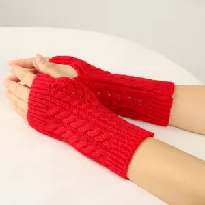 Close-up of red cable knit fingerless gloves showing textured patterns and soft material.