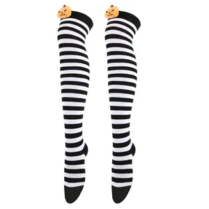 Detail showing pumpkin plush ornament on black and white striped over-the-knee socks