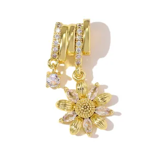 Macro detail of a gold daisy flower pendant set with sparkling marquise zircon stones.