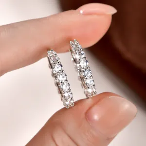 Vista macro detallada de pendientes de aro con diamantes brillantes sostenidos con la mano