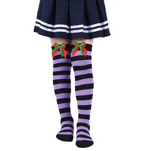 Close-up detail of purple and black striped girls socks with festive red and green bows