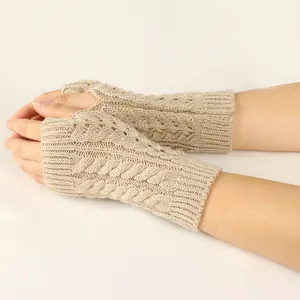 Close-up detail of beige cable knit fingerless gloves with openwork crochet patterns