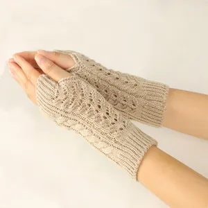 Detail view of beige cable-knit fingerless gloves showing intricate hollow-out pattern