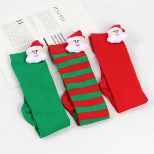 Close-up of children's Christmas knee-high socks with plush Santa Claus doll decorations