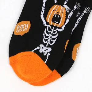Close-up of Halloween men's socks featuring pumpkin skeleton and "BOO!" text.