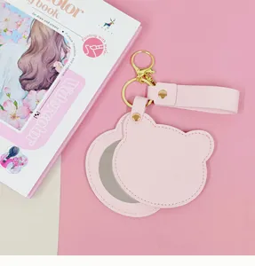 Vue détaillée d'un miroir de poche rose en cuir PU en forme d'ours avec un porte-clés doré