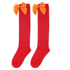 Detail of red children's knee-high socks with bright orange satin bows for Halloween