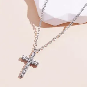 Detailed macro view of a silver cross pendant necklace with sparkling stone inlay