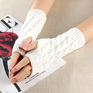 Close-up of white cable knit fingerless gloves showing texture and pattern details.