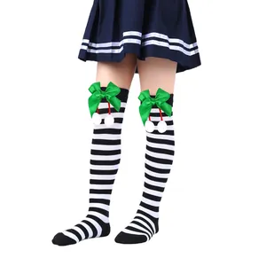 Detail view of children's Christmas over-the-knee socks with green bows and white pom-poms