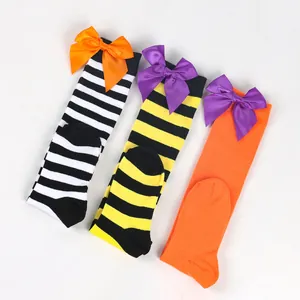 Detailed view of three pairs of children's Halloween over-the-knee socks with bows