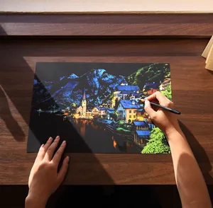 Detailed close-up of a person creating DIY city scenery scratch art on a wooden desk