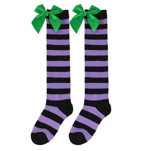 Detail of striped knee-high socks with green satin bows for girls' Christmas outfit.