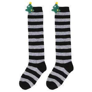 Detailed view of children's grey and black striped socks with plush Christmas trees.