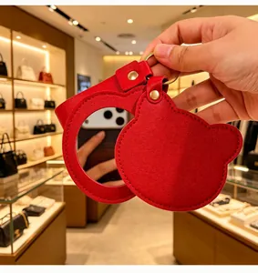 Gros plan d'un miroir de poche rouge en cuir PU en forme d'ours avec porte-clés