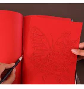 Détail d'un couteau sculptant un motif de papillon dans un livre de découpage de papier rouge DIY
