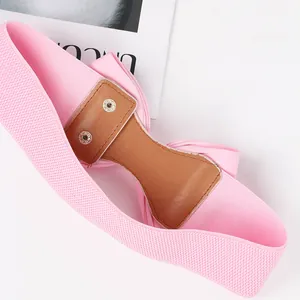 Detail view of pink elastic bow belt with brown faux leather back and snap buttons