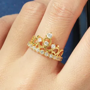 Vue macro détaillée d'une élégante bague couronne en or avec zircons 5A sur un doigt