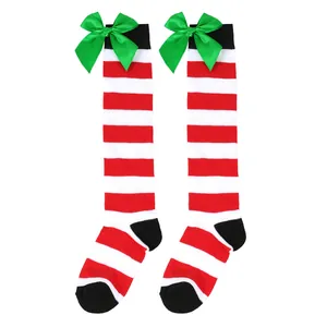 Close-up of red and white striped Christmas knee-high socks with large green bows