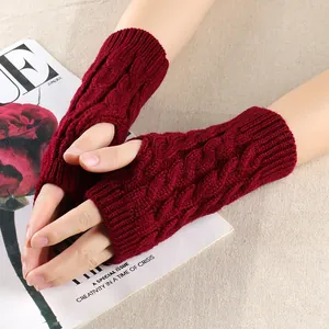 Detailed close-up of burgundy cable knit fingerless gloves showing the intricate twist pattern