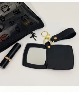 Détail d'un miroir de poche pliant en similicuir noir avec un anneau de porte-clés doré