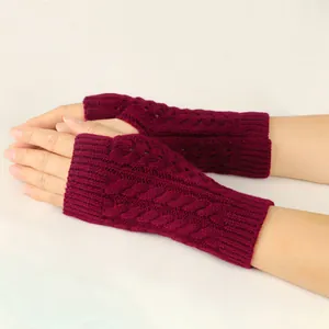 Close-up of burgundy cable knit fingerless gloves showing hollow-out pattern details.