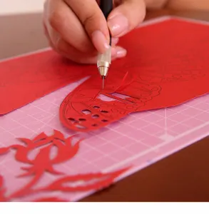 Gros plan du processus de sculpture sur papier DIY avec un couteau de précision sur du rouge