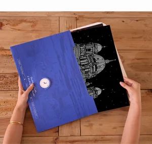 Hands revealing a detailed cityscape scratch art painting from a blue A3 size folder
