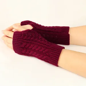 Close-up of burgundy cable knit fingerless gloves showing intricate hollow-out pattern detail.