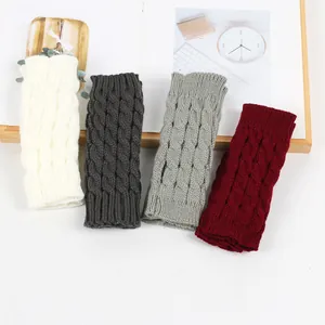 Close-up of four colors cable knit fingerless gloves showing the warm acrylic texture