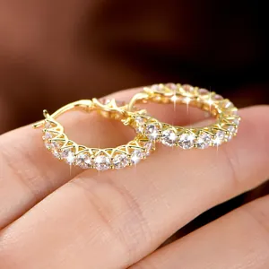 Primer plano de pendientes de aro bañados en oro de 14k con circonitas brillantes.