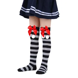 Detailed view of children's striped knee-high socks with red bows and pom-poms