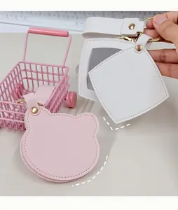 Détail d'un mignon porte-clés miroir de poche en cuir PU en forme d'ours et carré rose et blanc