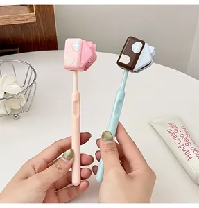 Primo piano di simpatici ganci per spazzolini a forma di casa tenuti da mani umane.