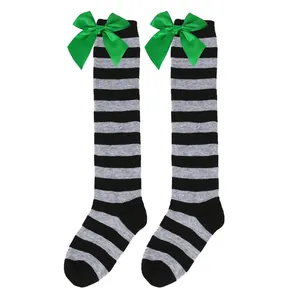 Detailed view of children's black and gray striped over-the-knee socks with green bows