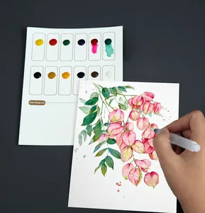 Detail showing a hand painting on professional watercolor paper with a built-in 12-color palette.