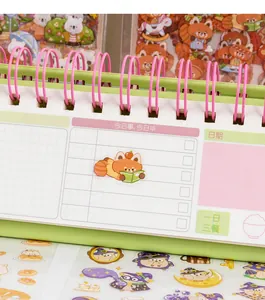 Close-up of cute cartoon red panda and owl stickers displayed on a green spiral notebook