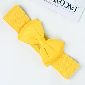 Close-up of a bright yellow elastic waist belt featuring a large decorative satin bow