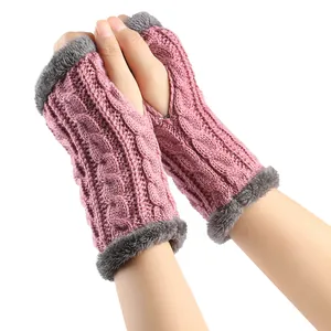 Détail de mitaines en tricot torsadé rose avec bordure en fausse fourrure grise.