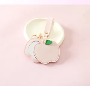 Detail view of pink PU leather apple-shaped mirror keychain with golden hardware