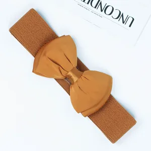 Detailed view of the mustard yellow elastic belt featuring a large chiffon bow