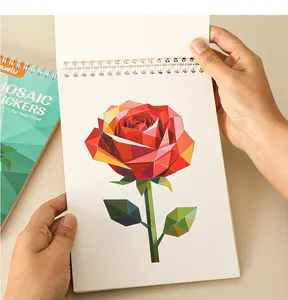 Hands flipping open a spiral sticker book to reveal a colorful geometric rose mosaic art.