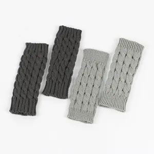 Detailed view of thick cable knit fingerless gloves in dark and light grey colors.