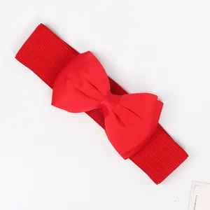 Detail view of a wide red elastic waist belt featuring a large chiffon bow ornament