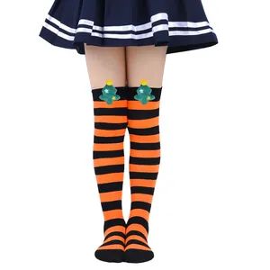 Detail view of kids' orange and black striped over-the-knee socks with plush Christmas tree.